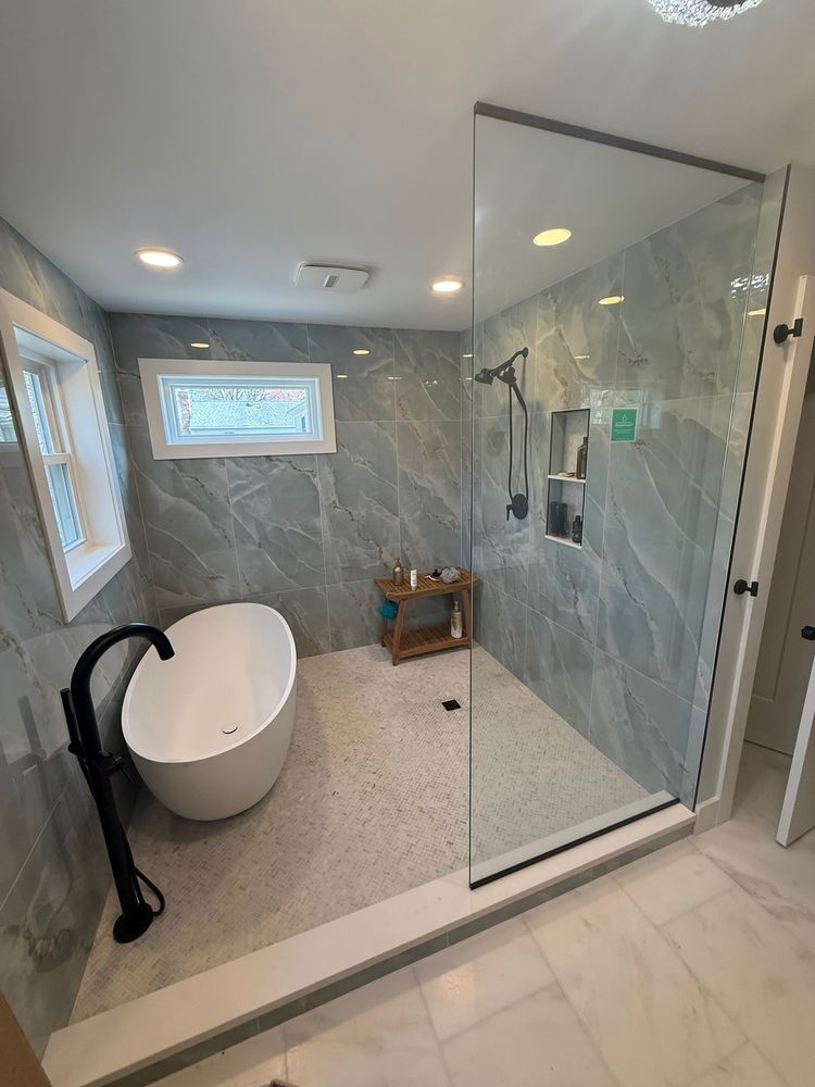 Frameless glass shower wall and door in a bright bathroom with a freestanding tub