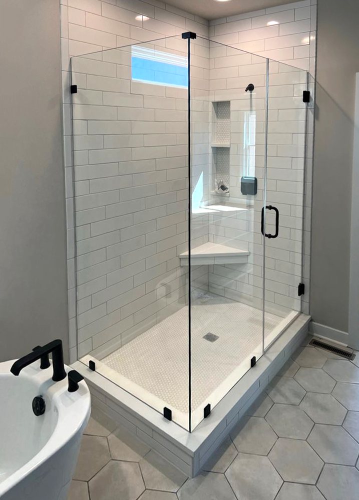 Frameless shower door and glass panel next to a soaking tub