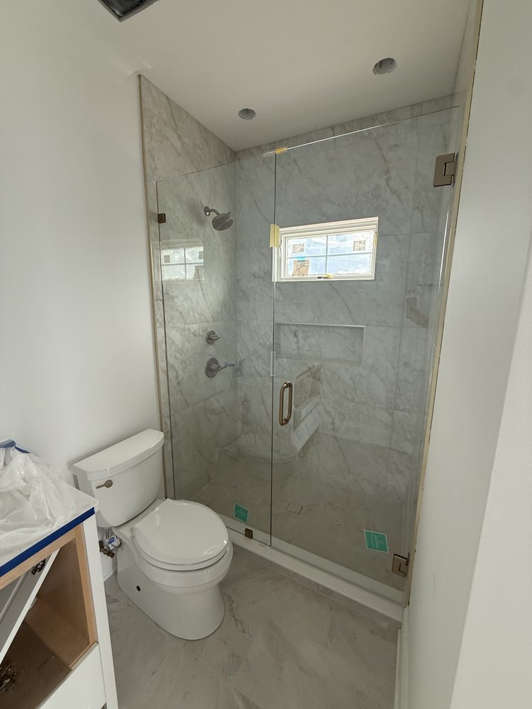 Frameless glass door and panel beside a toilet in a new-build bathroom