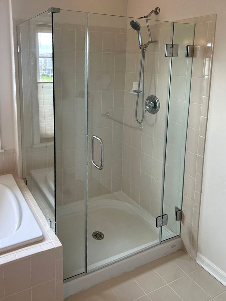 Frameless glass door and panel beside the same soaking tub, after replacement