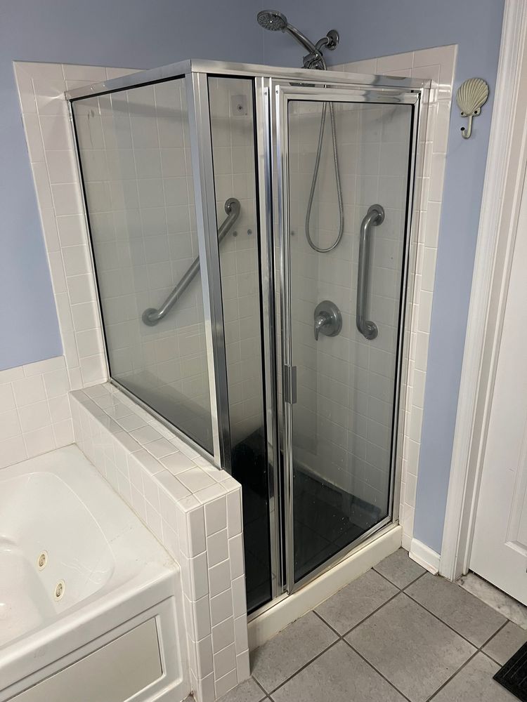 Framed shower door on a tile knee wall with a dark shower floor, before replacement