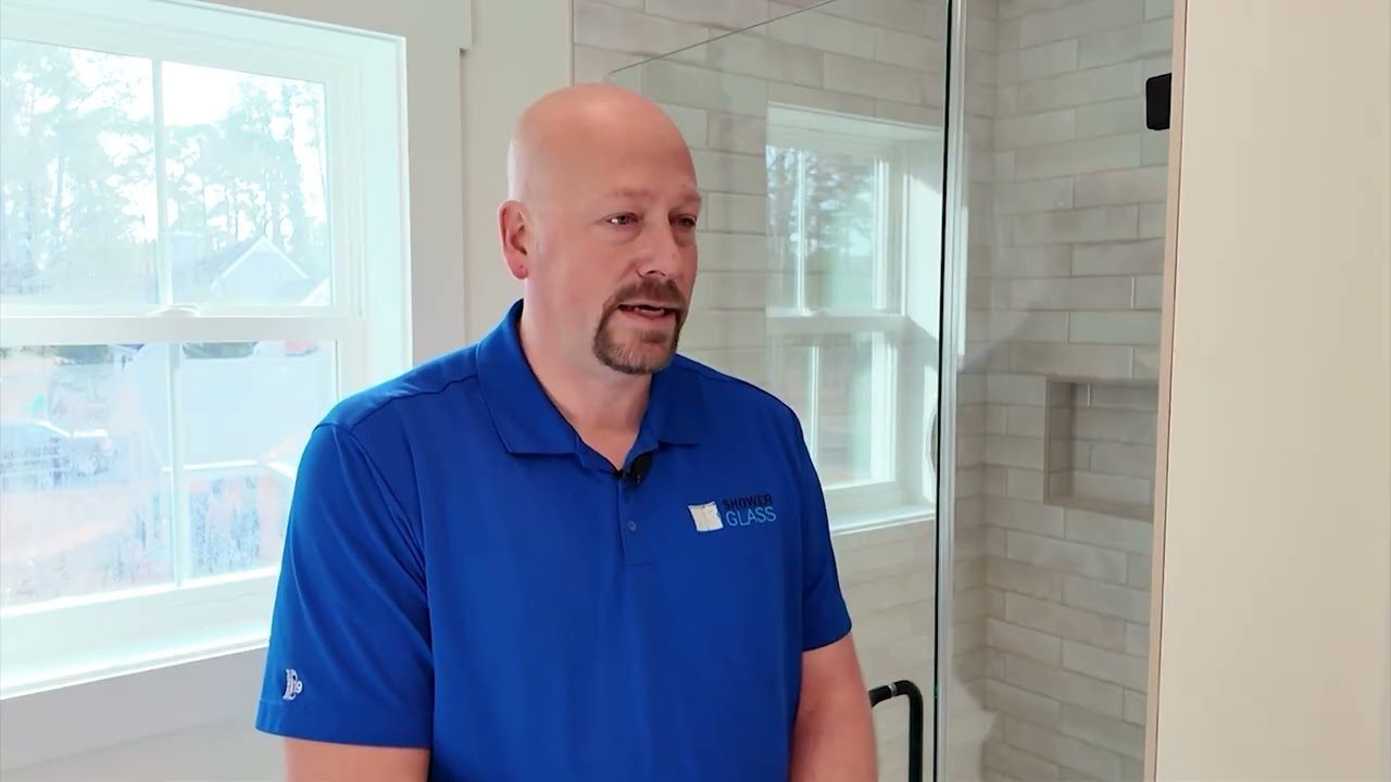 Jason Hickman, owner of Shower Glass, in a Shower Glass polo next to a frameless glass shower